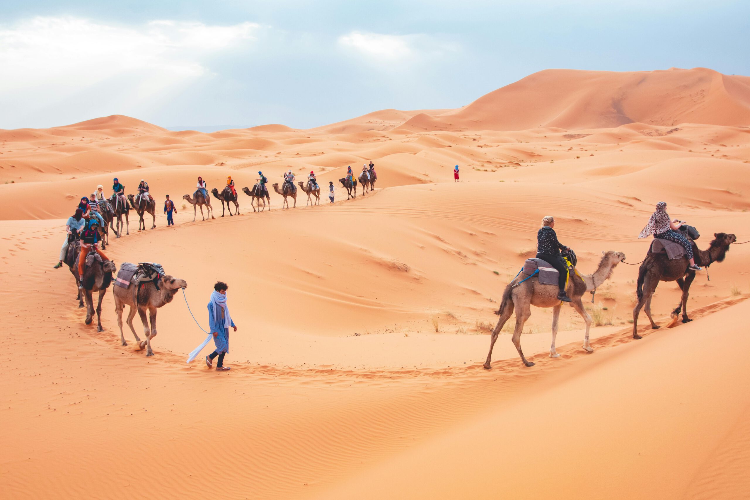 Tourists riding camels across the dunes of the Merzouga Desert